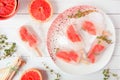 Healthy grapefruit and thyme ice pops, top view table scene against white wood