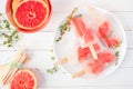 Healthy grapefruit and thyme popsicles, top view table scene against white wood