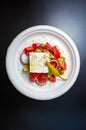 Healthy Greek salad in flat lay on black table surface.Delicious Mediterranean snack food served on recyclable paper plate.Good Royalty Free Stock Photo
