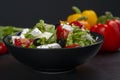 Healthy greek salad of fresh vegetables with tomatoes, lettuce, bell pepper, cucumbers, olives, feta cheese in plate on black ston Royalty Free Stock Photo