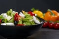 Healthy greek salad of fresh vegetables with tomatoes, lettuce, bell pepper, cucumbers, olives, feta cheese in plate on black ston Royalty Free Stock Photo