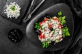 Healthy greek salad of fresh vegetables with tomatoes, lettuce, bell pepper, cucumbers, olives, feta cheese in plate on black Royalty Free Stock Photo