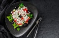 Healthy greek salad of fresh vegetables with tomatoes, lettuce, bell pepper, cucumbers, olives, feta cheese in plate on black Royalty Free Stock Photo