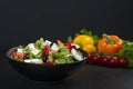 Healthy greek salad of fresh vegetables with tomatoes, lettuce, bell pepper, cucumbers, olives, feta cheese in plate on black ston Royalty Free Stock Photo