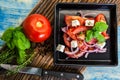 Healthy greek salad with tomatoes on a black plate over a wood board Royalty Free Stock Photo