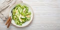 Healthy green avocado salad bowl with boiled eggs, sliced cucumbers, edamame beans, olive oil and herbs on ceramic plate Royalty Free Stock Photo