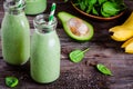 Healthy green smoothie with banana, spinach, avocado and chia seeds in glass bottles