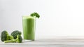 a healthy green smoothie, featuring broccoli, elegantly presented in a glass on a white wood background. The composition