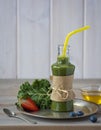 Healthy green smoothie with kale, strawberries, blueberries and honey in bottle with label on rustic wood background. Royalty Free Stock Photo