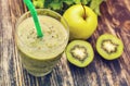Healthy green smoothie with kiwi, apple on rustic wood background, top view