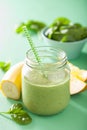 Healthy green spinach smoothie with mango banana in glass jar