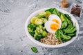 Healthy green vegetarian buddha bowl lunch with eggs, quinoa, spinach, avocado, grilled brussels sprouts and broccoli