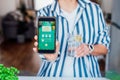 Healthy habit to drink water. Blurred woman with glass of pure water with lemon holding phone with active mobile app to