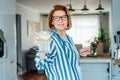 Healthy habit to drink water. Smiling middle age woman with glass of pure water with lemon standing on her kitchen