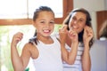 Healthy habits start from young. Portrait of an adorable little girl flossing her teeth with her mother at home. Royalty Free Stock Photo