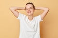 Healthy hair. Wellbeing wash. Pampering routine. Satisfied smiling woman wearing white T-shirt washes hair standing with shampoo