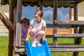 Healthy happy active young school age children, cheerful girls, sisters playing outdoors on the playground slide natural lifestyle Royalty Free Stock Photo