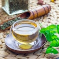 Herbal mint tea in oriental glass cup with fresh peppermint and tea scoop on background, square format Royalty Free Stock Photo