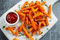 Healthy Homemade Baked Orange Sweet Potato Fries with ketchup, salt, pepper on white wooden board Royalty Free Stock Photo