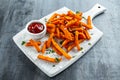 Healthy Homemade Baked Orange Sweet Potato Fries with ketchup, salt, pepper on white wooden board Royalty Free Stock Photo