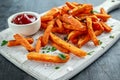 Healthy Homemade Baked Orange Sweet Potato Fries with ketchup, salt, pepper on white wooden board Royalty Free Stock Photo