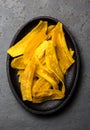 Healthy Homemade banana Plantain Chips on black plate, slate background