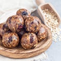 Healthy homemade energy balls with cranberries, nuts, dates and rolled oats on a wooden plate, square format