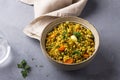 Healthy homemade food bowl with green buckwheat, vegetables, greens and curry with glass of water on gray textured background