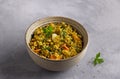 Healthy homemade food bowl with green buckwheat, vegetables, greens and curry with glass of water on gray textured background