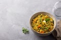 Healthy homemade food bowl with green buckwheat, vegetables, greens and curry with glass of water on gray textured background