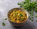 Healthy homemade food bowl with green buckwheat, vegetables, greens and curry with glass of water on gray textured background