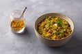 Healthy homemade food bowl with green buckwheat, vegetables, greens and curry with glass of water on gray textured background