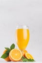 Healthy homemade lemonade - orange juice in wineglass with oranges and green leaves on white wood background, vertical. Royalty Free Stock Photo