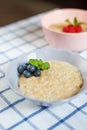 Healthy homemade oatmeal porridge with berries for breakfast in ceramic bowl on a checkered tablecloth. Royalty Free Stock Photo