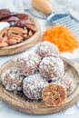 Healthy homemade paleo energy balls with carrot, nuts, dates and coconut flakes, on wooden plate