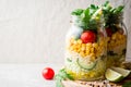 Healthy homemade salads with bulgur, vegetables and lime in mason jars on grey stone background.