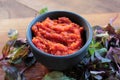 Healthy homemade tomato and red hot chili pepper sauce in a black bowl, and fresh basil on wooden board on table. Royalty Free Stock Photo