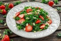 Healthy kale salad with strawberries and almond in a plate on wooden table