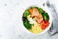 Healthy keto food concept. Fish salad bowl on marble background. Salad with salmon, couscous, vegetables, quail eggs Royalty Free Stock Photo