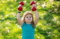 Healthy kid boy with dumbbell exercise outdoor. Little child practice dumbbells exercises in park.