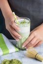 A healthy latte made from green tea. Cropped photo of girl`s hands with a glass of matcha tea