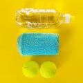 Healthy Life Sport Concept. Tennis Balls, Towel and Bottle of Water on Bright Yellow Background. Copy Space. Flat Lay