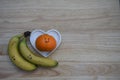 Healthy food photography image with fresh fruit of bananas and an orange with drawn on smile in love heart shape dish on wood Royalty Free Stock Photo