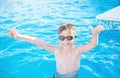 Healthy lifestyle. Active, happy nine years old child boy in sport goggles showing thumbs up on the swimming pool background.