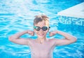 Healthy lifestyle. Active nine years old child boy in sport goggles in swimming pool. Child shows muscles, health force. Royalty Free Stock Photo