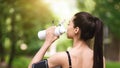Healthy Lifestyle Concept. Asian jogger girl drinking water, resting after running outdoors Royalty Free Stock Photo