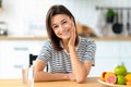 Healthy lifestyle cheerful young woman sits at home at the kitchen table with a glass of fresh clean water Royalty Free Stock Photo