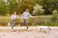 Excited couple and retriever running near lake Royalty Free Stock Photo