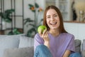 Healthy lifestyle. Happy beautiful young Caucasian woman with white teeth smiles broadly and holding fresh green apple Royalty Free Stock Photo