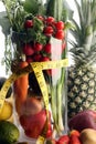 Healthy lifestyle concept. measuring tape sport fitness equipment and healthy food (fruits and vegetables, dumbells, apple, kiwi,